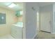 Practical laundry room with a washer, dryer, and convenient shelving for storage, next to a hallway at 8502 Crystal Cove Loop, Kissimmee, FL 34747