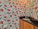 Powder room featuring floral wallpaper, granite countertop, single sink vanity, and a modern mirror at 8515 Saint Marino Blvd, Orlando, FL 32836