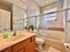 Bathroom featuring a shower-over-tub with glass doors, single sink vanity, and earth-toned tile at 8515 Saint Marino Blvd, Orlando, FL 32836