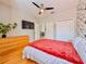 Bright bedroom with bamboo floors, ceiling fan, and a queen-sized bed with a red throw blanket at 8515 Saint Marino Blvd, Orlando, FL 32836