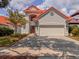 Charming two-story home featuring a red tile roof, a brick driveway and lush landscaping at 8515 Saint Marino Blvd, Orlando, FL 32836