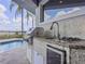 Covered outdoor kitchen with stainless steel grill, sink, gas burner, and a mini-fridge next to the pool at 8515 Saint Marino Blvd, Orlando, FL 32836