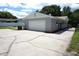 Side view of the home with large driveway, gray garage, and access gate at 8613 Edge O Woods Ct, Orlando, FL 32819