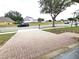 Paver driveway leading to a home on a tree-lined street with well-maintained lawns at 928 Chanler Dr, Haines City, FL 33844