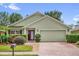 Charming home featuring a well-manicured lawn, brick driveway, and inviting front entrance at 9871 Nonacrest Dr, Orlando, FL 32832
