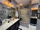 Stylish bathroom featuring double vanity sinks, framed mirrors, and a glass-enclosed shower at 10075 Sw 91St Pl, Ocala, FL 34481