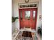 Close-up of the red front door with decorative glass, sidelights, and a colorful welcome mat at 10075 Sw 91St Pl, Ocala, FL 34481