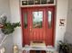 Elegant red front door with glass detailing, sidelights, and a decorative welcome mat at 10075 Sw 91St Pl, Ocala, FL 34481