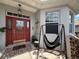 Covered front porch with a cozy hammock swing, vibrant red front door, and stylish tiled flooring at 10075 Sw 91St Pl, Ocala, FL 34481