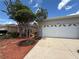 Attached two-car garage of a home featuring decorative windows and a concrete driveway at 10075 Sw 91St Pl, Ocala, FL 34481