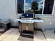 Backyard patio featuring a stainless-steel grill, window, and stucco wall at 10075 Sw 91St Pl, Ocala, FL 34481