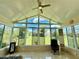 Bright sunroom with large windows offering beautiful views of the well-maintained backyard and a ceiling fan at 10075 Sw 91St Pl, Ocala, FL 34481
