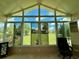 Sunroom with large windows offering serene backyard views, a ceiling fan, and neutral decor at 10075 Sw 91St Pl, Ocala, FL 34481