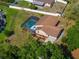 Aerial view of a home with a screened-in pool, landscaping, and mature trees in a residential area at 10545 Parkway Dr, Clermont, FL 34711