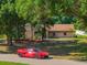 Quaint single-story brick home nestled among mature trees with a red Corvette parked out front at 10545 Parkway Dr, Clermont, FL 34711