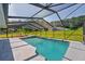Beautiful screened in pool area with lush green yard and tropical trees in the distance at 10545 Parkway Dr, Clermont, FL 34711
