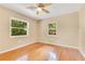 Bright bedroom featuring hardwood floors, two windows, a ceiling fan and neutral wall paint at 12046 Se 135Th Ave, Ocklawaha, FL 32179
