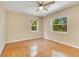 Bright bedroom featuring hardwood floors, two windows, a ceiling fan and neutral wall paint at 12046 Se 135Th Ave, Ocklawaha, FL 32179