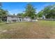 Large backyard with a pool, patio, mature trees, partial wooden fence and back view of home at 16 Lake Drive, Debary, FL 32713