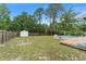 Spacious backyard with a pool, storage shed, privacy fence, and mature trees at 16 Lake Drive, Debary, FL 32713
