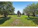 Expansive front yard with lush green grass and mature trees leading to the charming home at 16249 Se 162Nd Ct, Weirsdale, FL 32195