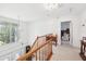 Bright upstairs hallway with natural light, wood banister, and an elegant chandelier at 16249 Se 162Nd Ct, Weirsdale, FL 32195