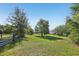 Expansive green lot viewed through an open gate showcasing a serene and private home setting at 16249 Se 162Nd Ct, Weirsdale, FL 32195