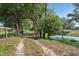 Property view of the long driveway entrance with a pond and lush trees creating an inviting scene at 16249 Se 162Nd Ct, Weirsdale, FL 32195