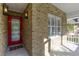 Close-up of the front porch showcasing a bright red front door, sidelight, and brick facade at 25 Reflections Village Dr, Ormond Beach, FL 32174
