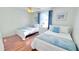 Cozy bedroom with two twin beds, hardwood floors, and a sunny window with white curtains at 3129 Arrow Dr, Kissimmee, FL 34746