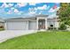 Inviting single-story home featuring a well-manicured lawn, three-car garage, and a charming American flag at 4002 Richmond Xing, Leesburg, FL 34748