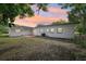 A view of the backyard with a white block home, lush trees and setting sunlight at 7301 Armstrong Rd, Orlando, FL 32810