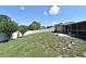Large, grassy backyard with white vinyl fence, mature trees and access to screened lanai at 8625 Shady Glen Dr, Orlando, FL 32819