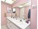 Bright bathroom with double sink vanity, framed mirror, and stylish pink walls at 8625 Shady Glen Dr, Orlando, FL 32819