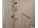 Close-up of a tiled shower with adjustable shower head, convenient corner shelves, and a safety grab bar at 8625 Shady Glen Dr, Orlando, FL 32819