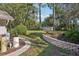 Manicured backyard with lush landscaping, mature trees, retaining wall, and storage shed at 921 Torchwood Dr, Deland, FL 32724