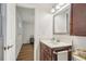 Bathroom featuring wood cabinets, mirror, sink, toilet, and hardwood floors in the hallway at 921 Torchwood Dr, Deland, FL 32724