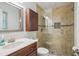 Bathroom with cherry cabinets, marble countertop, and tiled shower with glass door at 921 Torchwood Dr, Deland, FL 32724