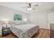 Bright bedroom featuring hardwood floors, ceiling fan, closet, and a comfortable queen bed with floral bedding at 921 Torchwood Dr, Deland, FL 32724