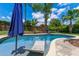 Backyard pool with chair, umbrella, and a playground beyond. Lush, mature landscaping surrounds the perimeter of the yard at 986 Stonewood Ln, Maitland, FL 32751