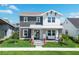 Charming two-story home with a cozy front porch swing, lush lawn and vibrant landscaping on a sunny day at 10183 Peebles St, Orlando, FL 32827