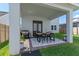 Covered outdoor patio with dining set, grill, and lush green lawn, perfect for entertaining and relaxation at 10183 Peebles St, Orlando, FL 32827