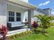 Inviting front porch with a cushioned porch swing, palm trees and colorful foliage that creates a relaxing ambiance at 10183 Peebles St, Orlando, FL 32827