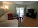 The living room features a large beige couch, wood-look floors, and a sliding glass door to the backyard at 110 N Alderwood St, Winter Springs, FL 32708