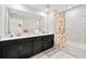 Well-lit bathroom featuring double sinks, vanity, shower with glass door and stylish floral shower curtain at 1128 Challenge Dr, Davenport, FL 33896