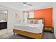 Bright bedroom with white linens, modern furniture, and a vibrant orange accent wall at 1128 Challenge Dr, Davenport, FL 33896