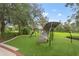 Community playground area featuring climbing structure on synthetic grass with surrounding mature trees at 136 Triplet Lake Dr, Casselberry, FL 32707