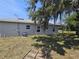 Rear exterior view of house showing windows, gray exterior paint, covered patio and large shade tree in the backyard at 141 W G H Washington St, Apopka, FL 32703