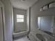 Bathroom with tiled bathtub and modern vanity with recessed sink and bright vanity lighting at 141 W G H Washington St, Apopka, FL 32703