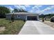 Exterior shot showing concrete driveway and open garage of newly built single-story home under cloudy blue skies at 141 W G H Washington St, Apopka, FL 32703